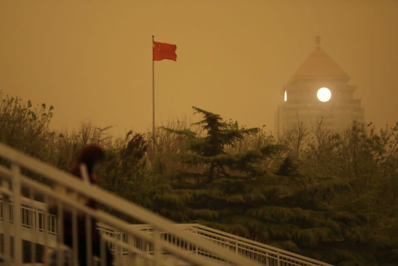 Pedestrian walks near a Chinese flag amid a duststorm in Beijing