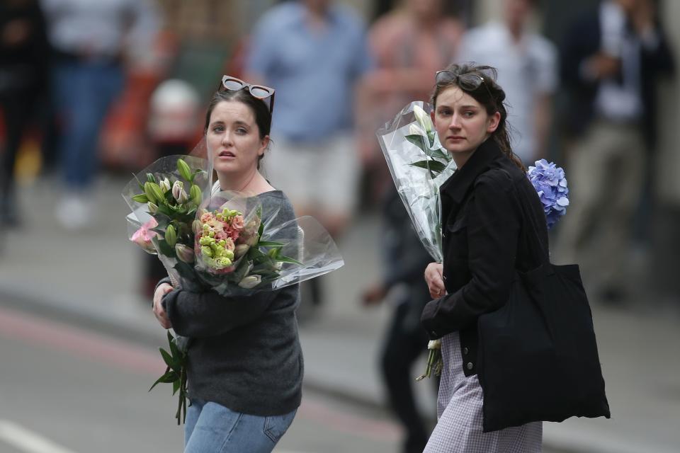 Women arrive at the north end of London Bridge with flowers.&nbsp;