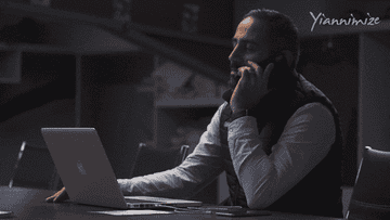 a man with a laptop and on his phone sitting at a table