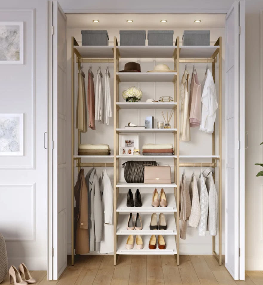 gold and white toned closet organizer with clothes and shoes stored