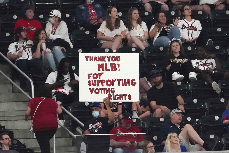 FILE - This photo from Monday April 26, 2021, shows a fan holding a sign supporting Major League Baseball's decision to move the All Star Game from Atlanta, during a baseball game between theChicago Cubs and the Atlanta Braves in Atlanta, Georgia. A Manhattan judge has rejected an attempt to force Major League Baseball to return next month's All-Star Game to Atlanta, after it was moved to Denver after Georgia Republicans enacted a restrictive new voting law. (AP Photo/John Bazemore, File).