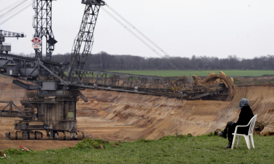 A person sits in a chair next to the Garzweiler lignite opencast mine at the village Luetzerath near Erkelenz, Germany, Tuesday, Jan. 10, 2023. A court in Germany has rejected a last-ditch attempt by climate activists to stay in an abandoned village which is due to be cleared for the expansion of a coal mine that's become a battleground between the government and environmentalists. (AP Photo/Michael Probst)