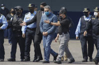 Former Honduran President Juan Orlando Hernandez, center, is taken in handcuffs to a waiting aircraft as he is extradited to the United States, at an Air Force base in Tegucigalpa, Honduras, Thursday, April 21, 2022. Honduras' Supreme Court approved the extradition of Hernandez to the United States to face drug trafficking and weapons charges. (AP Photo/Elmer Martinez)
