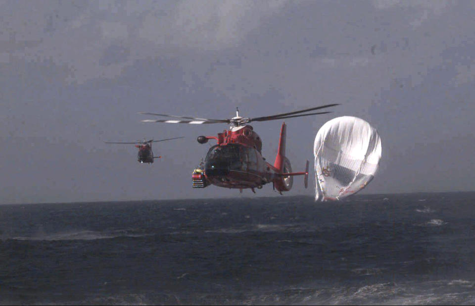 FILE - Two Coast Guard choppers head for Barbers Point Naval Air Station after rescuing British billionaire Richard Branson, American millionaire Steve Fossett and Per Lindstrand of Sweden, 15 miles north of Kahuku Point on Oahu, Hawaii, after their failed attempt to make the first nonstop round-the-world flight in a balloon on Dec. 25, 1998. The massive hunt for the Titan submersible that imploded deep in the North Atlantic has refocused attention on whether wealthy risktakers should pay for emergency search and rescue efforts. (George F. Lee/Honolulu Star-Advertiser via AP, File)