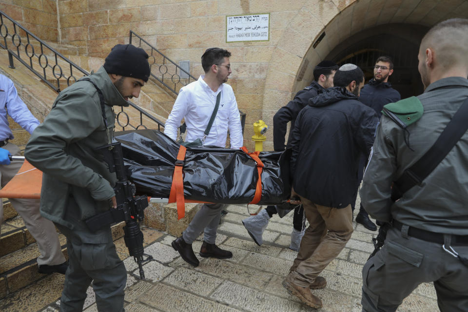 Israeli security personnel and members of Zaka Rescue and Recovery team carry the body of a Palestinian man who was fatally shot by Israeli police after he killed one Israeli and wounded four others in a shooting attack in Jerusalem's Old City, Sunday, Nov. 21, 2021. (AP Photo/Mahmoud Illean)