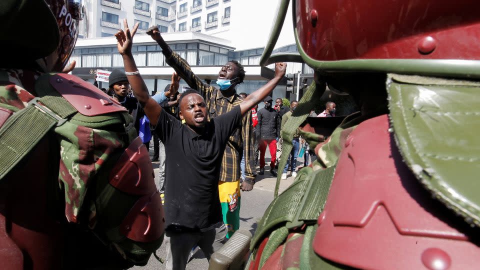 Demonstrators react as police stand guard - Monicah Mwangi/Reuters