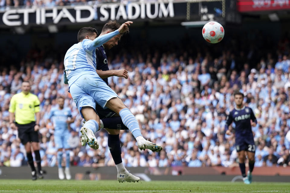 Manchester City's Joao Cancelo, left, fails to stop Aston Villa's Matty Cash from scoring his sides first goal during the English Premier League soccer match between Manchester City and Aston Villa at the Etihad Stadium in Manchester, England, Sunday, May 22, 2022. (AP Photo/Dave Thompson)