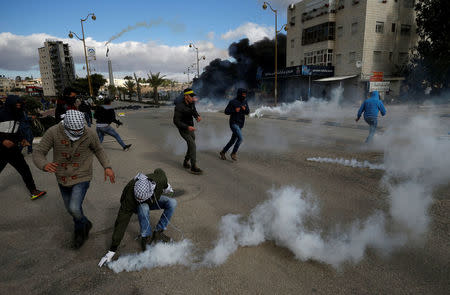 Palestinian protesters react to tear gas fired by Israeli troops during clashes at a protest against U.S. President Donald Trump's decision to recognize Jerusalem as the capital of Israel, near the Jewish settlement of Beit El, near the West Bank city of Ramallah December 7, 2017. REUTERS/Mohamad Torokman