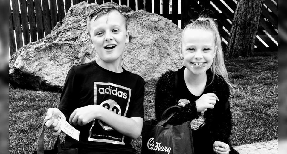 A black and white photo of John and Lacey Bennett sitting down holding bags with Cadbury written on them.