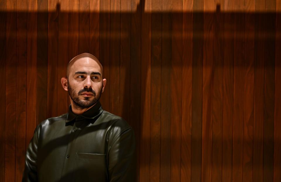 An actor against a wooden backdrop poses for the camera.