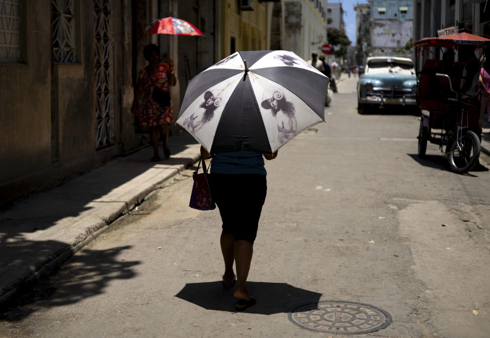 A pedestrian shades herself with an umbrella in Havana, Cuba, Wednesday, July 5, 2023. The entire planet sweltered for the two unofficial hottest days in human record keeping Monday and Tuesday, according to University of Maine scientists at the Climate Reanalyzer project. (AP Photo/Ramon Espinosa)