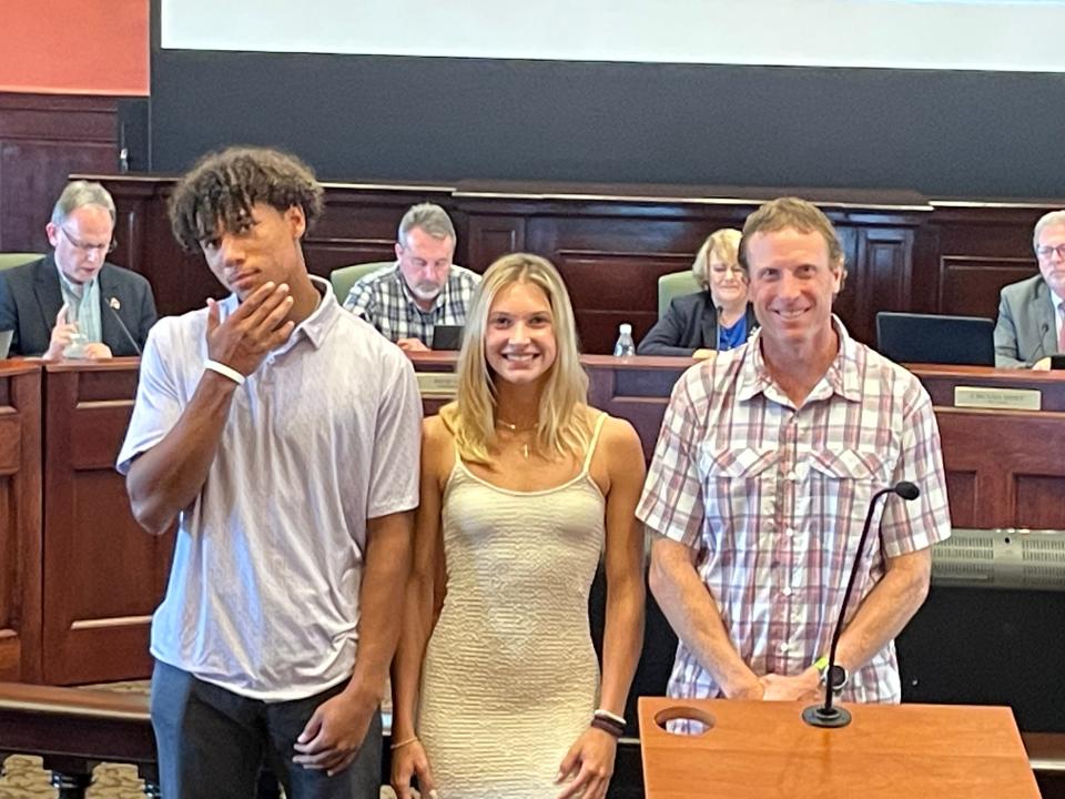 West Henderson track and field athletes Tayman Howell, left, and Emma Hall, center, pose with girls coach Aaron Saft at the June 5 Henderson County Board of Commissioners meeting. Hall and Howell were recognized for winning state titles.