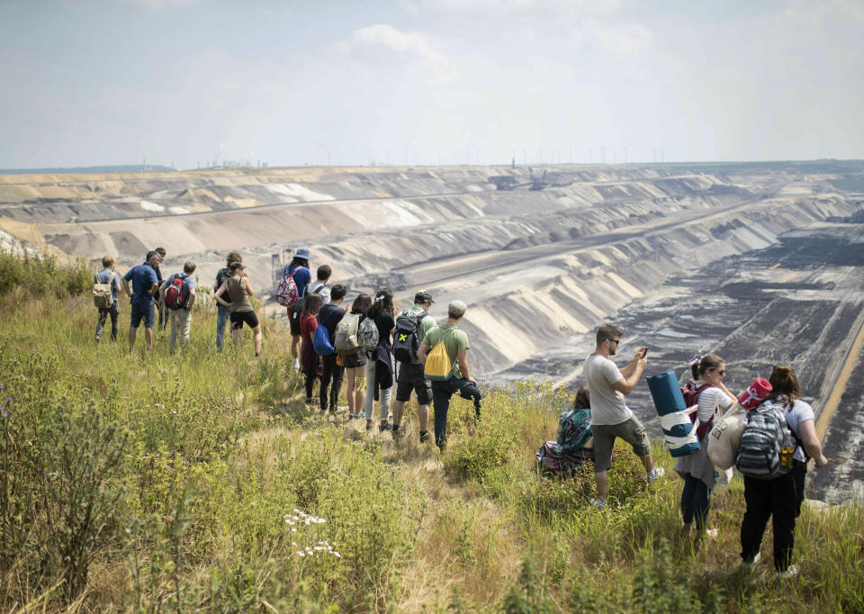 Numerous environmental activists walk on a roadway on the site of the Garzweiler open-cast mine in Garzweiler, Germany, Saturday, June 22, 2019. The protests for more climate protection in the Rhineland continue. (Marcel Kusch/dpa via AP)