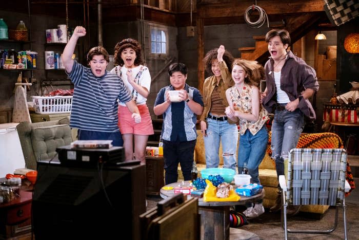 Cast of That '90s Show jumping for joy in the basement in a scene from the new series