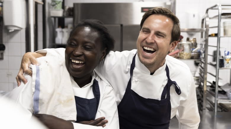 Two chefs laughing in a kitchen