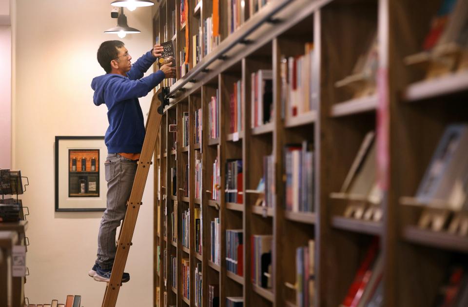 Albert Wan who along with his wife Jenny Smith are co-owners of Bleak House Books, stocks the shelves with books that recently arrived.