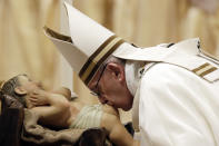 Pope Francis kisses a statue of Baby Jesus as he celebrates the Christmas Eve Mass in St. Peter's Basilica at the Vatican, Monday, Dec. 24, 2018. (AP Photo/Alessandra Tarantino)