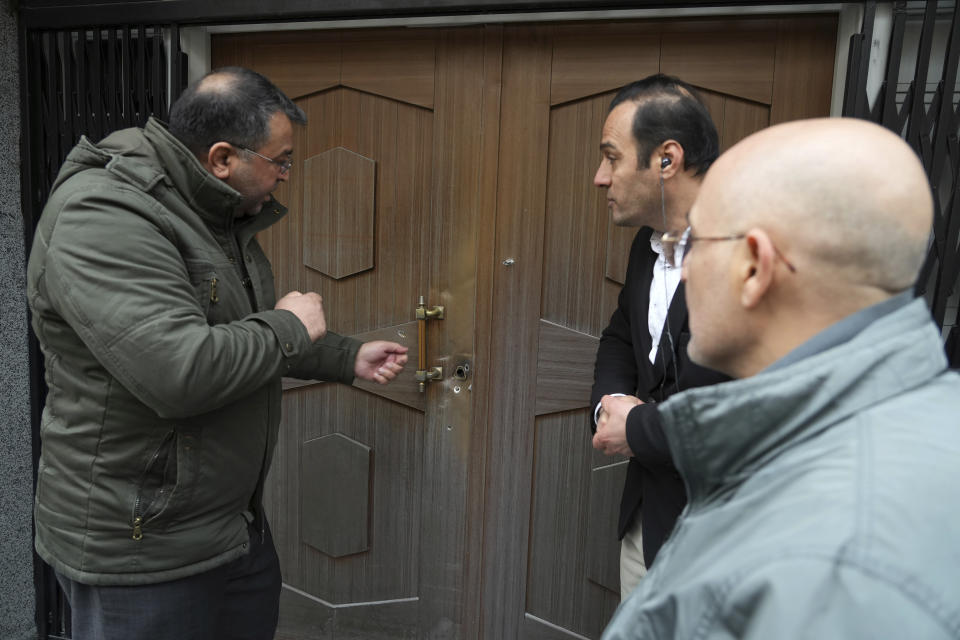 A man gestures at bullet holes left after an attack at the Azerbaijan Embassy in Tehran, Iran, Friday, Jan. 27, 2023. A man armed with a Kalashnikov-style rifle stormed the Azerbaijan Embassy in Iran's capital Friday, killing the head of security at the diplomatic post and wounding two guards, authorities said. (AP Photo/Vahid Salemi)