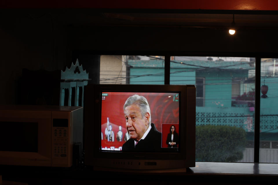 Mexico's President Andres Manuel Lopez Obrador is seen on a TV screen as Rafael Silva watches the live broadcast of the president's daily, morning press conference known as "La Mañanera" at his home in Neza, Mexico State, on the outskirts of Mexico City, Friday, Dec. 18, 2020. Every morning Rafael meets his brother Gustavo for breakfast after dropping his wife off at work and they both watch Obrador's morning press conference. (AP Photo/Rebecca Blackwell)