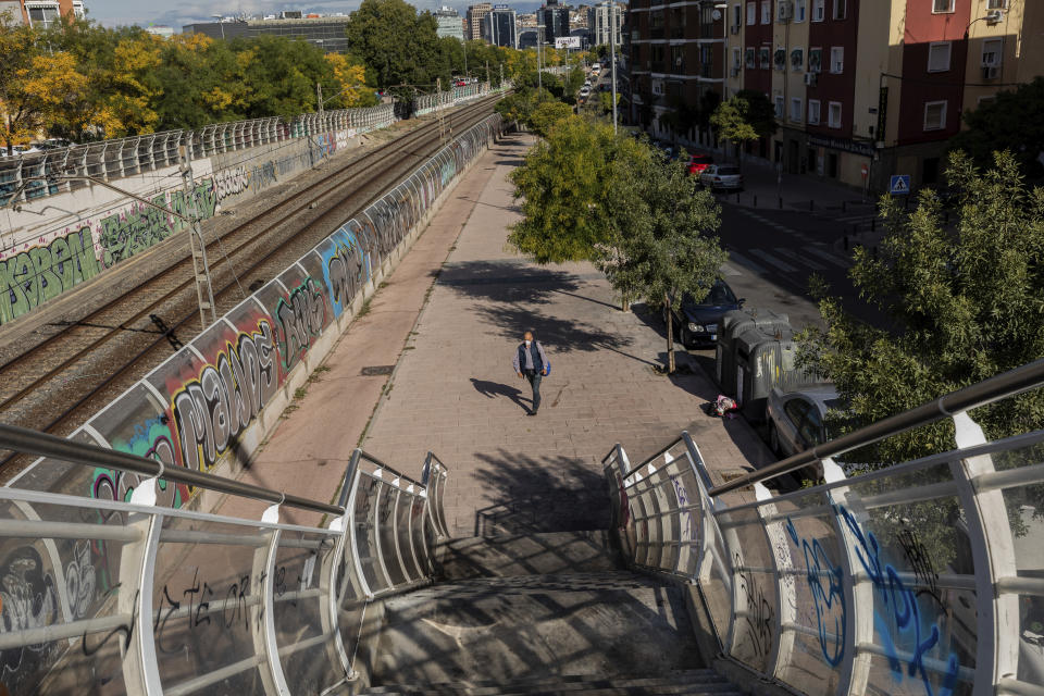 A man wearing a face mask to prevent the spread of the coronavirus walks in the southern neighbourhood of Vallecas in Madrid, Spain, Thursday, Oct. 1, 2020. Madrid and its suburbs are preparing to enter a soft lockdown that restricts trips and out of the Spanish capital following a weeks-long political turf fight over Europe's latest infection hot spot. (AP Photo/Bernat Armangue)