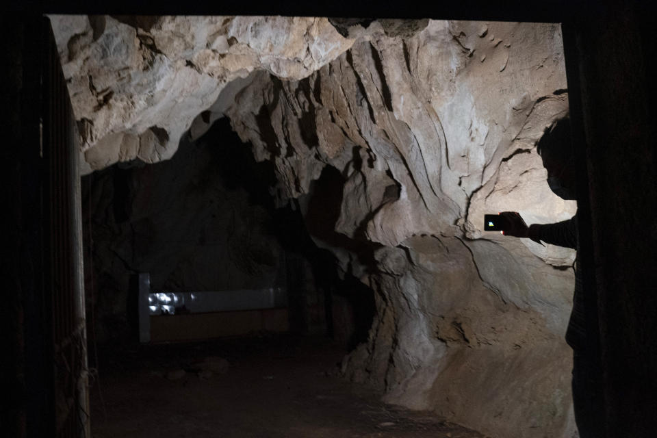 A man shines a light in the abandoned Wanling cave near Manhaguo village in southern China's Yunnan province on Wednesday, Dec. 2, 2020. Villagers said the cave had been used as a sacred altar presided over by a Buddhist monk _ precisely the kind of contact between bats and people that alarms scientists. (AP Photo/Ng Han Guan)