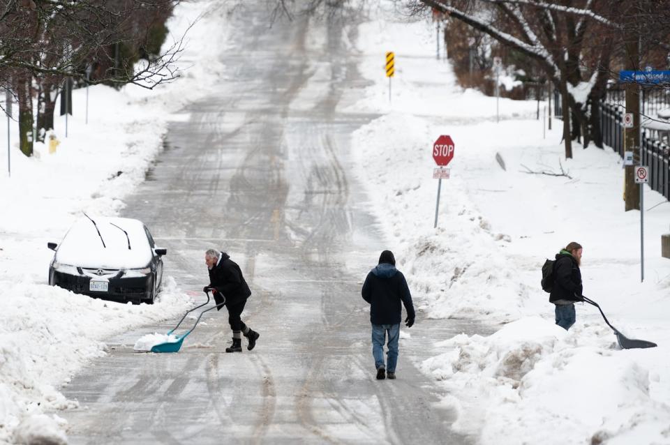 People shovel snow in the Sandy Hill neighbourhood of Ottawa, on Friday, Dec. 23, 2022. (Spencer Colby/The Canadian Press - image credit)