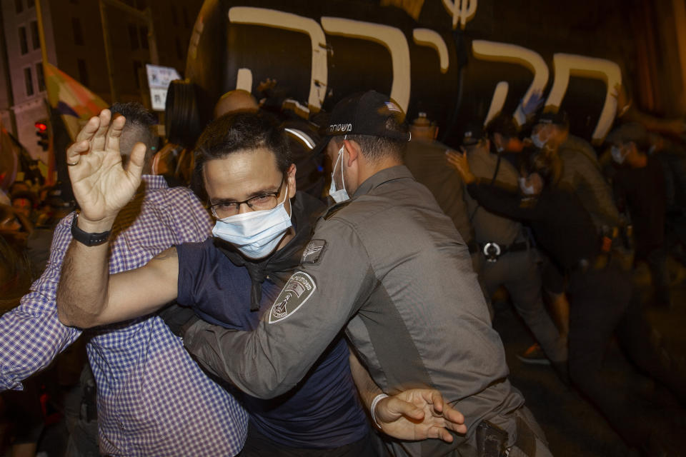 Israeli police officers scuffle with protesters near Israeli Prime Minister Benjamin Netanyahu's residence in Jerusalem, Saturday, Sept. 5, 2020. The writing say "Investigation". (AP Photo/Ariel Schalit)