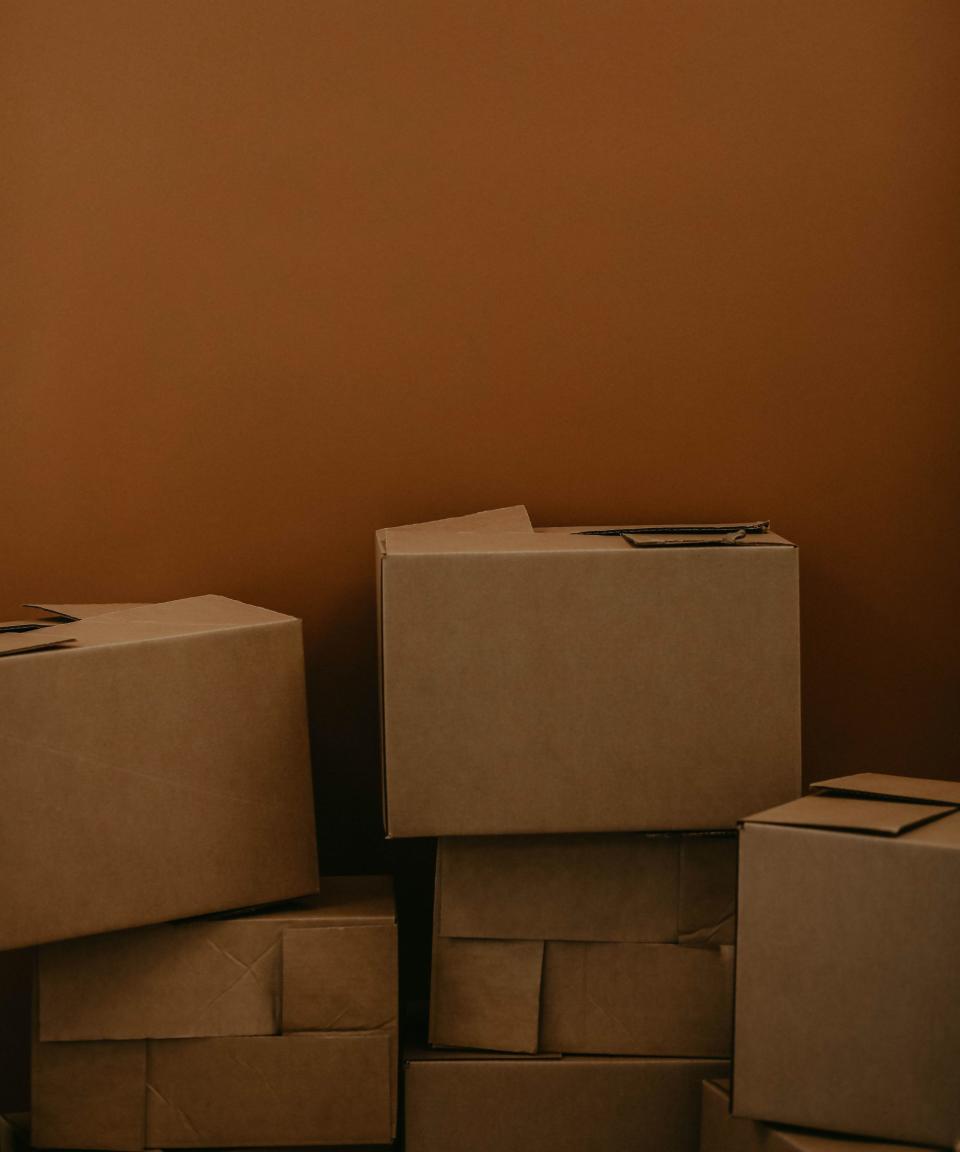 Brown cardboard moving boxes in front of a brown painted wall