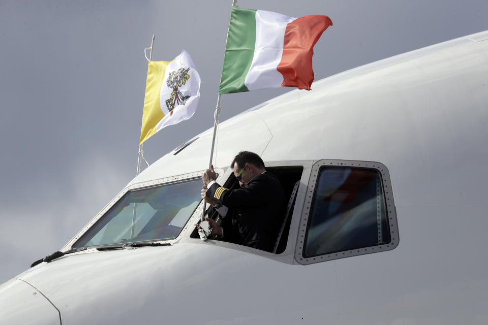 An Alitalia pilot set the Italian flag beside the Vatican flag outside the cockpit prior to the arrival of Pope Francis on the occasion of the first ever trip to United Arab Emirates at Rome's Fiumicino International airport, Sunday, Feb. 3, 2019. (AP Photo/Gregorio Borgia)