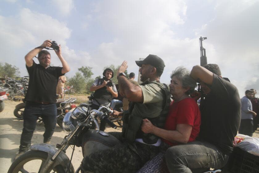 Palestinians transport a captured Israeli civilian, center, from Kibbutz Kfar Azza into the Gaza Strip on Saturday, Oct. 7, 2023. The militant Hamas rulers of the Gaza Strip carried out an unprecedented, multi-front attack on Israel at daybreak Saturday, firing thousands of rockets as dozens of Hamas fighters infiltrated the heavily fortified border in several locations by air, land, and sea and catching the country off-guard on a major holiday. (AP Photo/Hatem Ali)