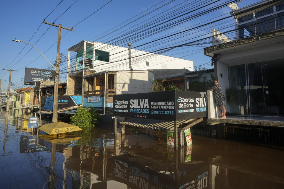 A resident stands on the balcony of his home partially submerged by flood waters from heavy rains, in Porto Alegre, Rio Grande do Sul state, Brazil, Thursday, May 9, 2024. (AP Photo/Andre Penner)