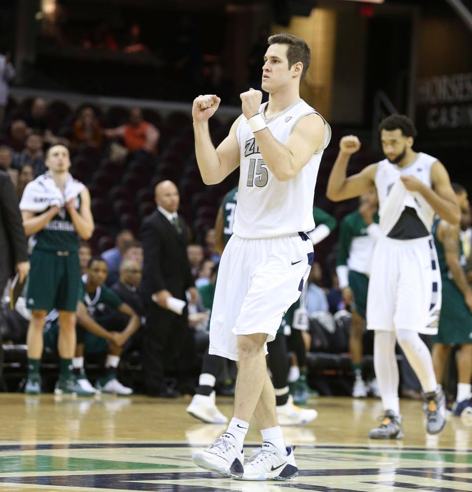 Akron's Jake Kretzer (center) and Kwan Cheatham Jr. celebrate as a last-second desperation shot by Eastern Michigan falls short giving the Zips a Mid-American Conference tournament quarterfinal win in Cleveland.