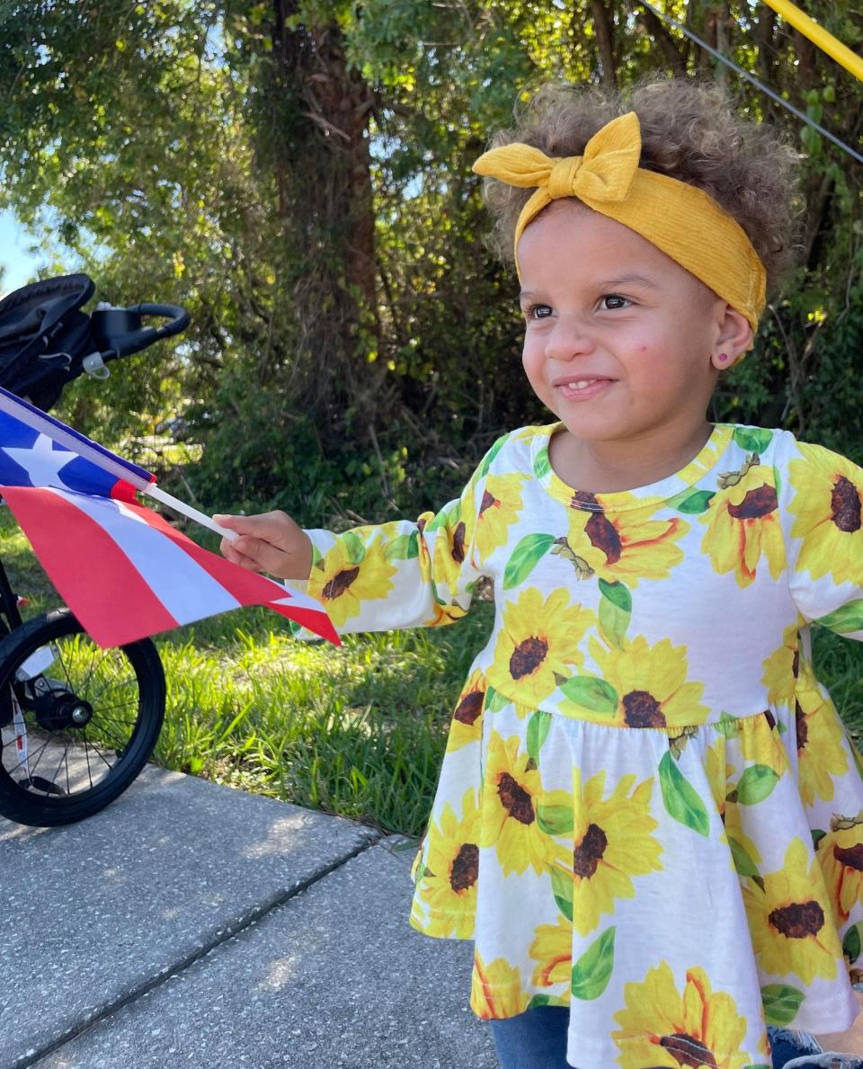 Ellie James, age 2, attended the parade with her mother, Erin Julian. She waved a Puerto Rican flag as a marching band passed.