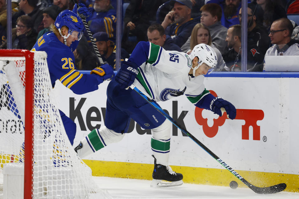 Buffalo Sabres defenseman Rasmus Dahlin (26) and Vancouver Canucks right wing Ilya Mikheyev (65) battle for the puck behind the net during the second period of an NHL hockey game, Tuesday, Nov. 15, 2022, in Buffalo, N.Y. (AP Photo/Jeffrey T. Barnes)