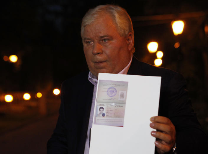 Lawyer Anatoly Kucherena shows a picture of fugitive former U.S. spy agency contractor Edward Snowden in his new refugee documents granted by Russia during a news conference in Moscow August 1, 2013. Snowden slipped quietly out of the airport on Thursday after securing temporary asylum in Russia, ending more than a month in limbo in the transit area.  REUTERS/Maxim Shemetov (RUSSIA - Tags: POLITICS CRIME LAW)