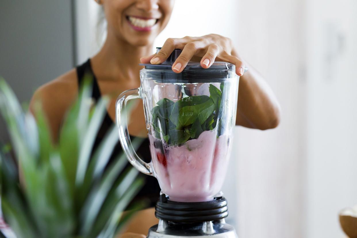 Woman blending a healthy smoothie with spinach