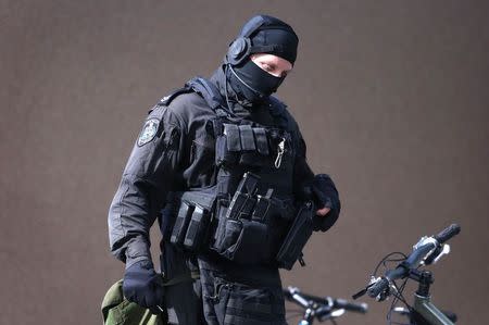 A heavily armed police officer walks near Lindt cafe, where hostages are being held,in Martin Place in central Sydney December 15, 2014. REUTERS/David Gray