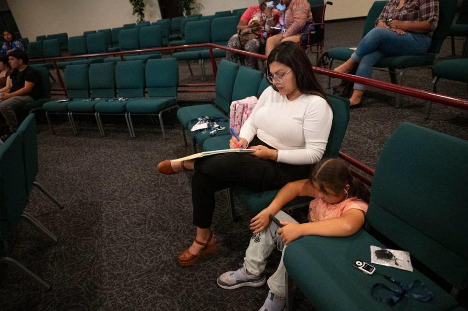 Prisila Isais takes notes as her daughter Isabel, 8, a Sacramento City Unified School District student, watches a video on her phone while attending a Sacramento ACT town hall meeting about community schools at South Sacramento Christian Center on April 12. 