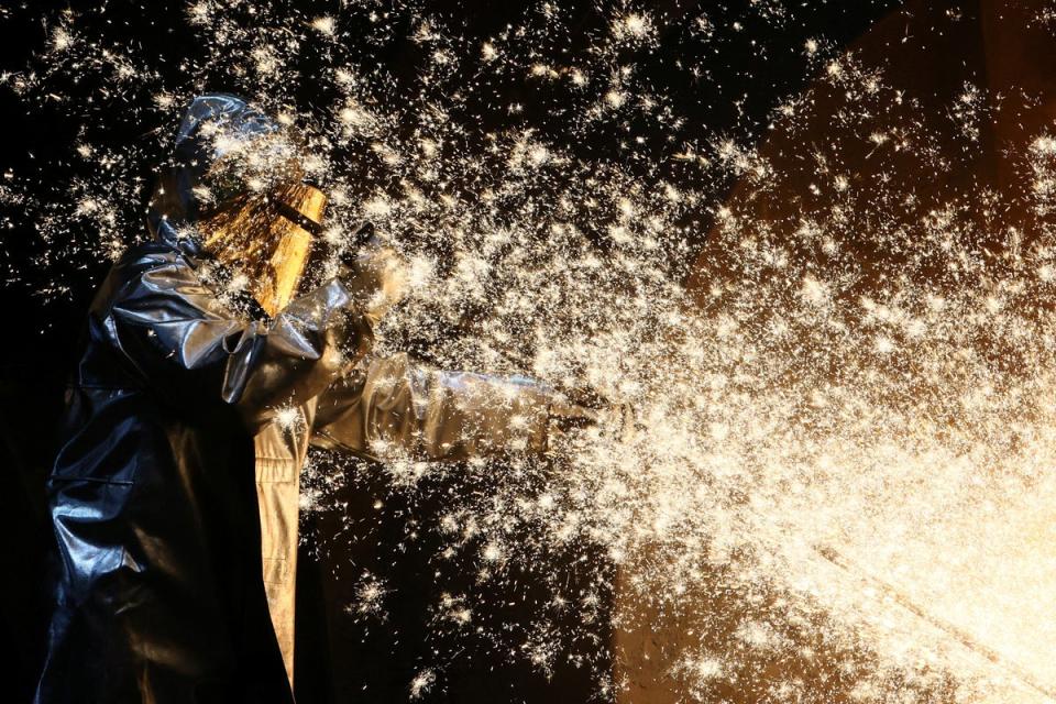 A steel worker of ThyssenKrupp stands amid sparks of raw iron coming from a blast furnace at a ThyssenKrupp steel factory in Duisburg, western Germany (Reuters)