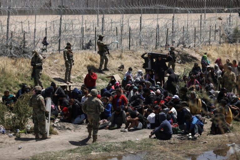 Migrantes de diferentes nacionalidades rezan delante de unos agentes antidisturbios de la Guardia Nacional de Texas que impiden que crucen la frontera en Ciudad Juárez, México, el 16 de abril de 2024 (Herika Martínez)