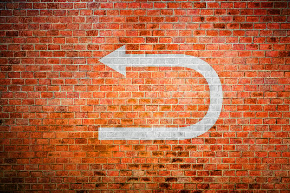 A return symbol painted on the brick wall.