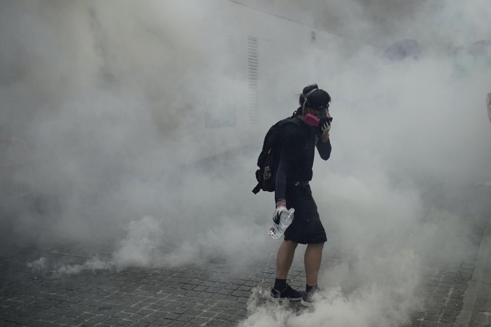 An anti-government protester walks through tear gas smoke during a clash with police at the Wong Tai Sin area in Hong Kong, Tuesday, Oct. 1, 2019. Thousands of black-clad pro-democracy protesters defied a police ban and marched in central Hong Kong on Tuesday, urging China's Communist Party to "return power to the people" as the party celebrated its 70th year of rule. (AP Photo/Felipe Dana )