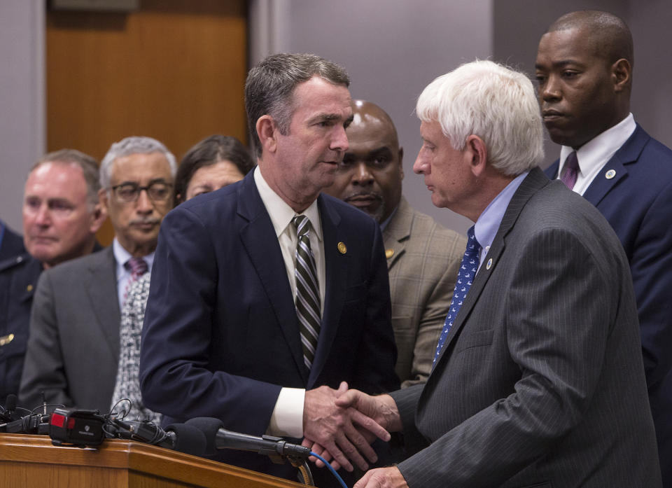 Virginia Gov. Ralph Northam , center, shakes the hand of Virginia Beach (Va.) Mayor Bobby Dyer after giving remarks during a news conference regarding the shooting at a municipal building,Friday, May 31, 2019, in Virginia Beach. A longtime city employee opened fire in a municipal building in Virginia Beach on Friday, killing several people on three floors and sending terrified co-workers scrambling for cover before police shot and killed him following a "long gun-battle," authorities said. (Kaitlin McKeown/The Virginian-Pilot via AP)