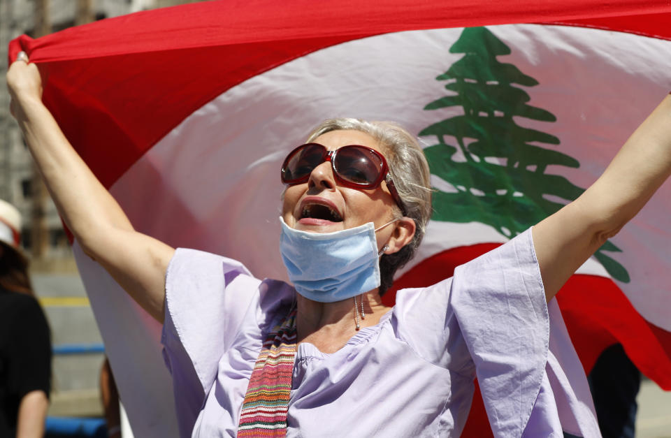 An anti-government protester holds a Lebanese flag and shouts slogans during a protest against a general amnesty law being proposed in parliament, in Beirut, Lebanon, Thursday, May 28, 2020. (AP Photo/Hussein Malla)