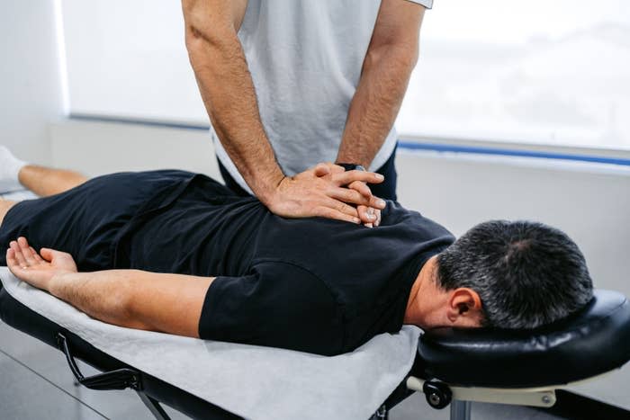 Une personne recevant un ajustement chiropratique sur une table de massage, vue du dessus, les mains du thérapeute sur le dos