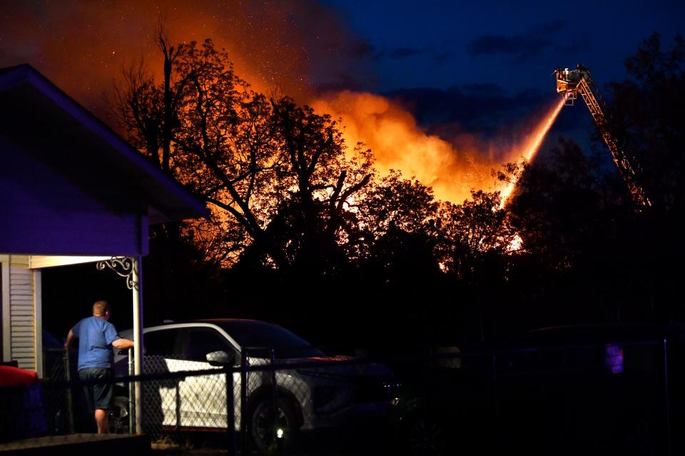 A resident in the 1300 block of Cypress Street watches from his porch as Abilene firefighters pour water onto the burning St. Ann Hospital Thursday.