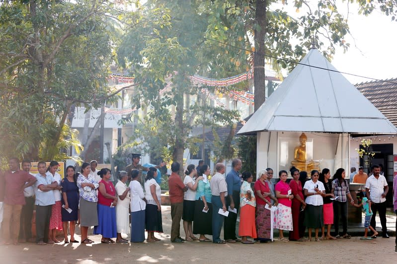 People stand in a line to cast their vote during the presidential election in Colombo