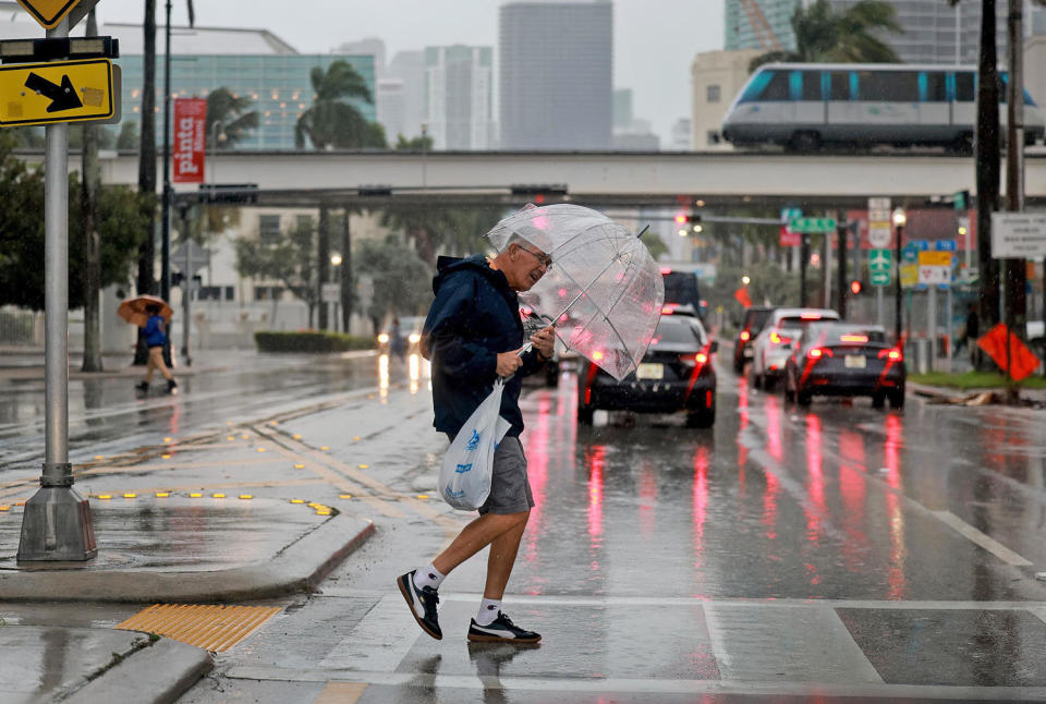 A pedestrian crosses the street in a rain storm on Nov. 15, 2023 in Miami. (Joe Raedle / Getty Images)