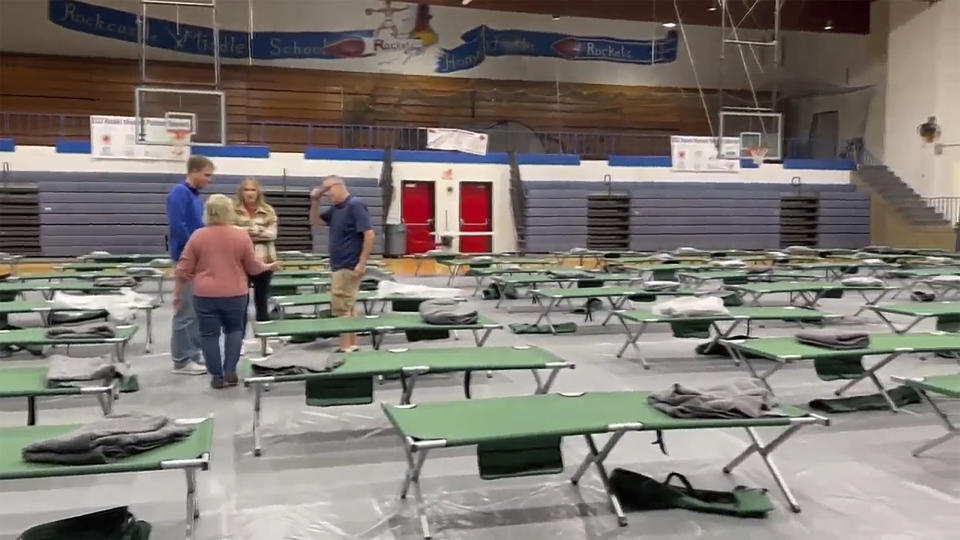 This image taken from video and provided by WTVQ shows people helping arrange cots at Rockcastle Middle School, being used as an evacuation center, in Mt Vernon, Ky., Wednesday, Nov. 22, 2023. People were evacuated from a nearby town after a CSX train derailed Wednesday near Livingston, a remote town with about 200 people in Rockcastle County. CSX says two of the 16 cars that derailed carried molten sulfur, which caught fire after the cars were breached. (WTVQ via AP)