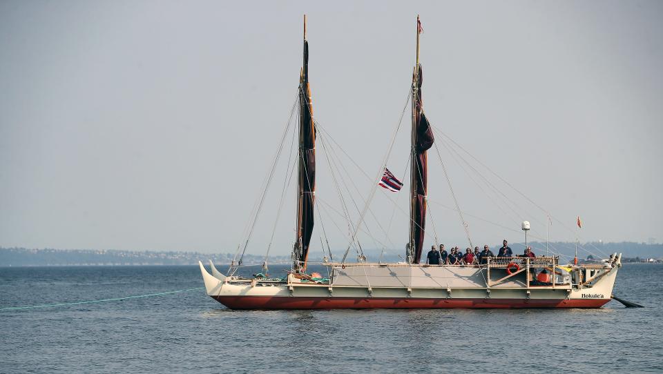 The traditional Polynesian Voyaging Canoe Hōkūleʻa is towed by a boat past the shoreline as they ask permission to land in Suquamish on Aug. 24.